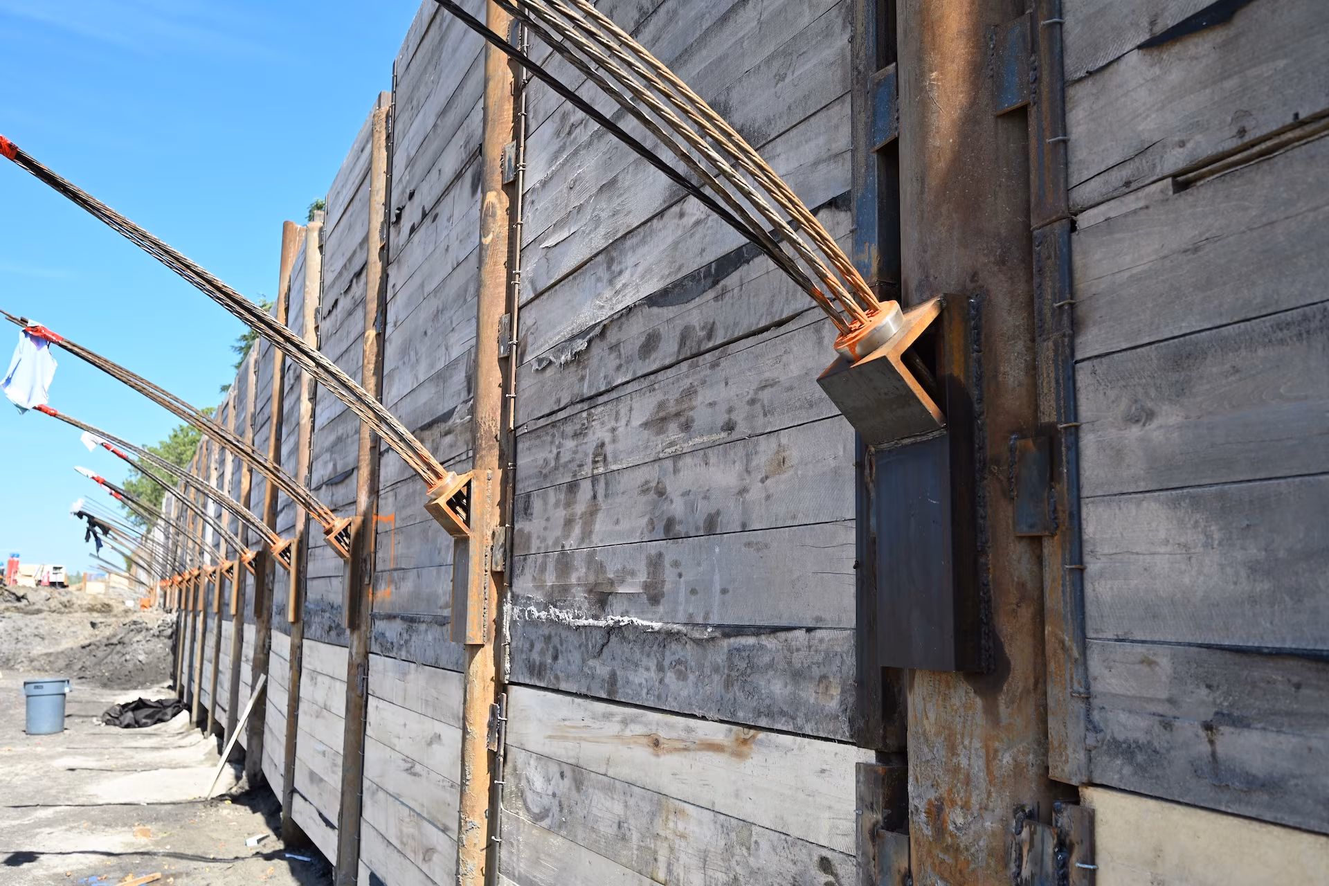 Mur de soutènement en bois renforcé par des câbles d'acier tendus fixés à des supports métalliques.